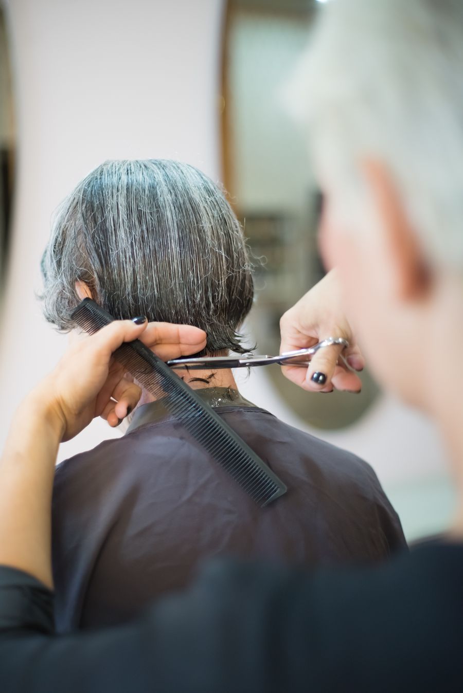 Stylist cutting a woman's bob with scissors and comb