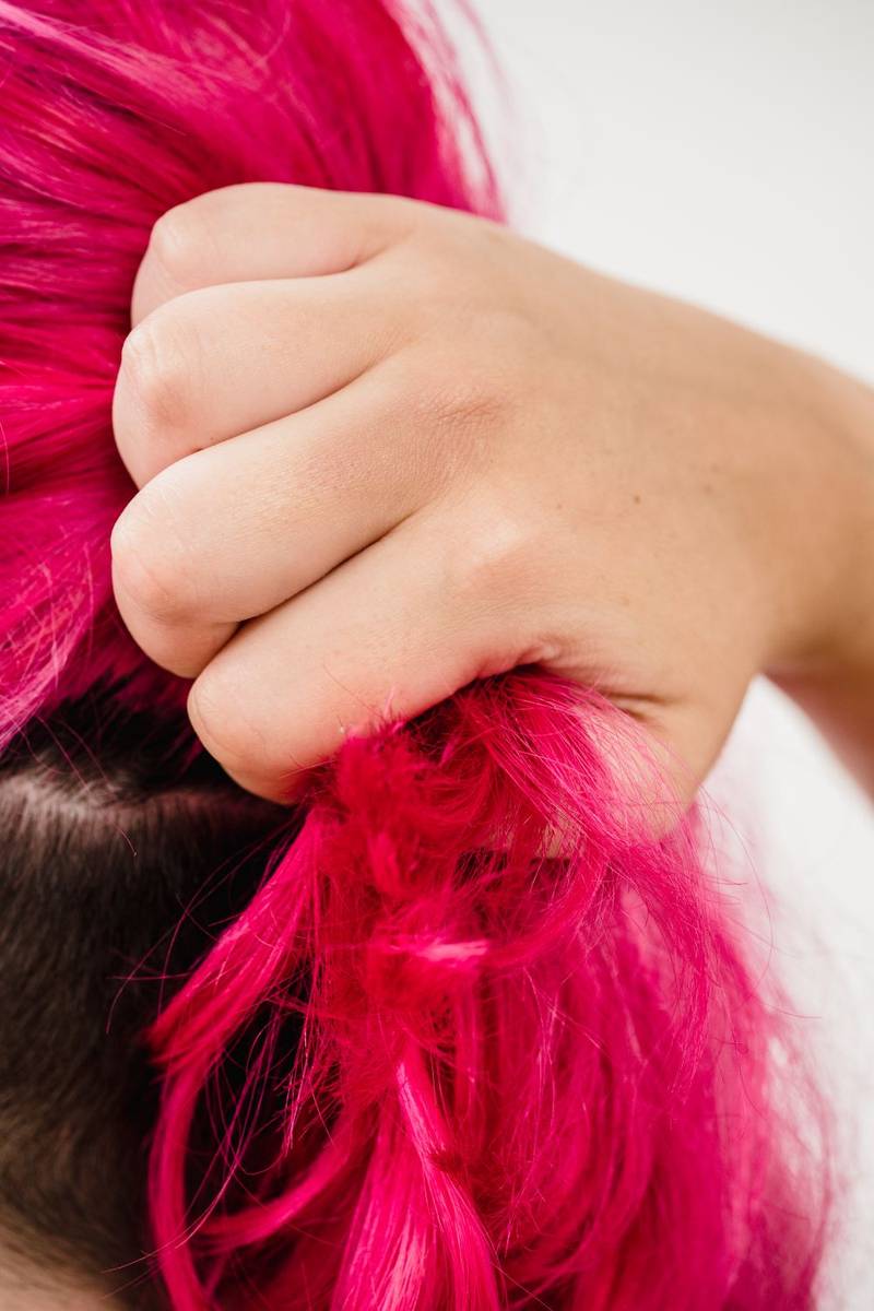 Vivid hot-pink hair held in a hand